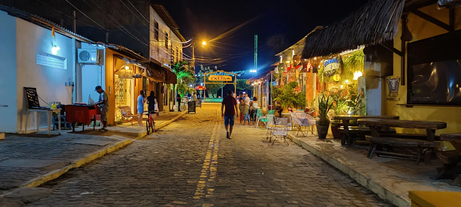 Rua da Xêpa at night: cobbled street with lit shops and restaurant terraces under the XEPA sign