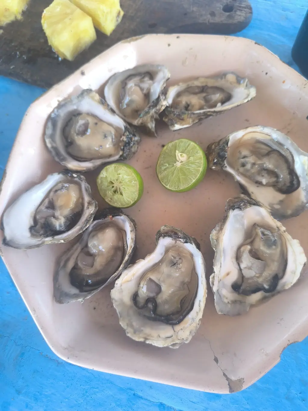 Plate of fresh oysters with lime halves on a blue table