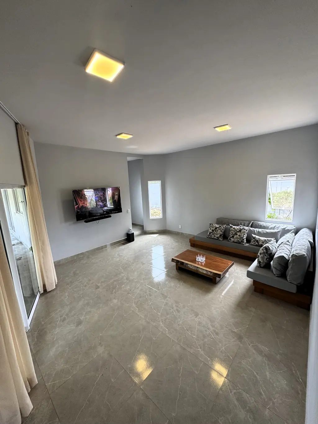 Living room with grey sofas, a low wooden coffee table, wall-mounted TV and polished floor